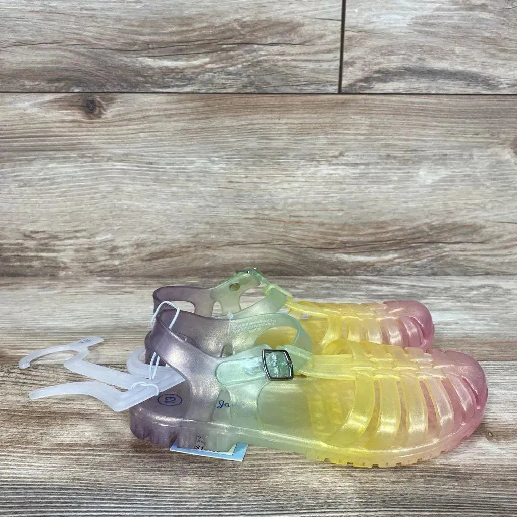 Side view of Cat & Jack jelly sandals, size 13C, translucent yellow-to-pink gradient with buckled ankle strap on wood