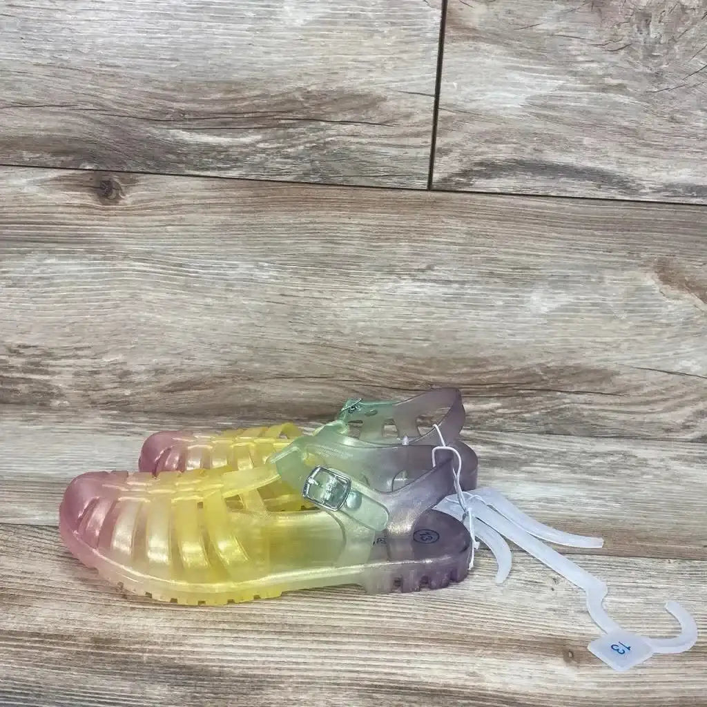 Side view of Cat & Jack jelly sandals, size 13C, translucent yellow-to-purple gradient with buckle strap on wood floor