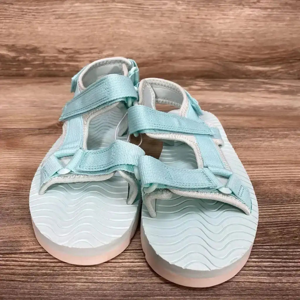 Front view of turquoise Cat & Jack Emery toddler sandals with adjustable ankle and toe straps and wavy footbed on wood background