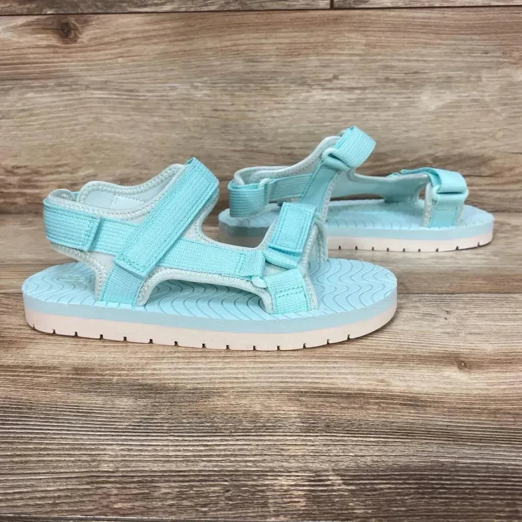 Side view of turquoise Emery ankle strap sandals size 3Y showing adjustable straps and textured footbed on wood background