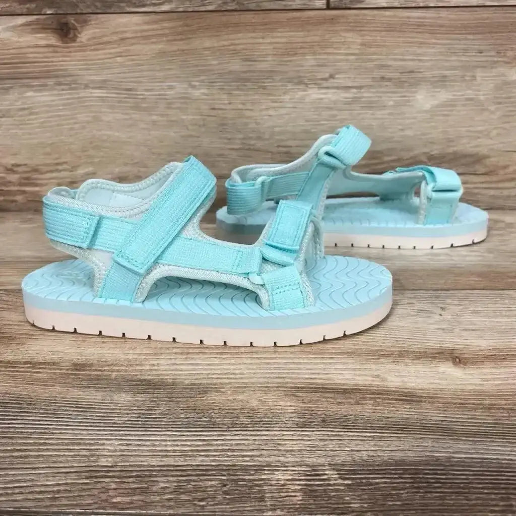 Side view of turquoise Emery ankle strap sandals size 3Y showing adjustable straps and textured footbed on wood background