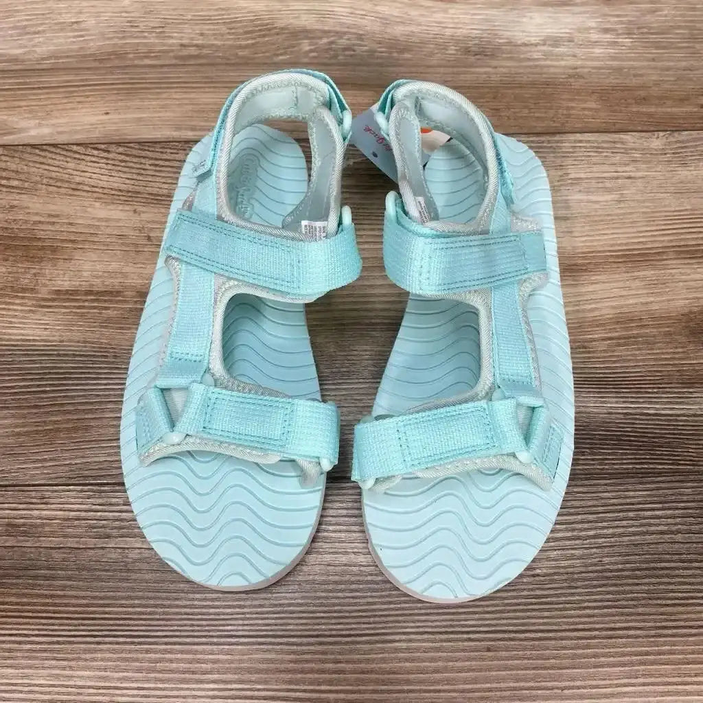 Top view of NEW Cat & Jack Emery Ankle Strap Sandals sz 3Y showcasing light teal sport sandals with hook-and-loop straps on wood plank background