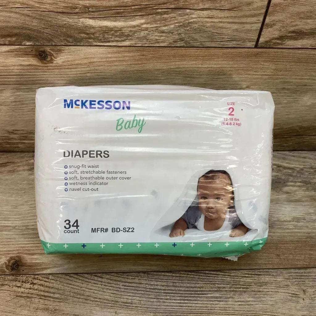 Front view of McKesson diaper pack (Size 2, 12–18 lb, 34 count) showcasing package front with baby photo and feature list on wood background