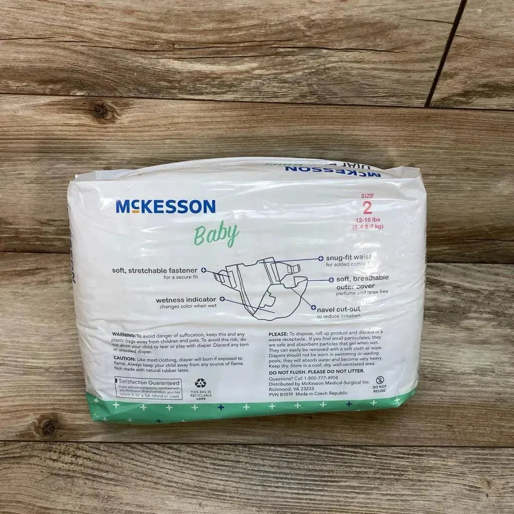 Front of McKesson Baby diapers pack, size 2 (12-18 lb), showing wetness indicator and stretchable fastener on wood background