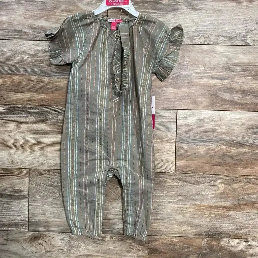 Front view of green Penelope Mack Henley jumpsuit 12M with ruffle sleeves, henley placket, elastic ankles on wood floor