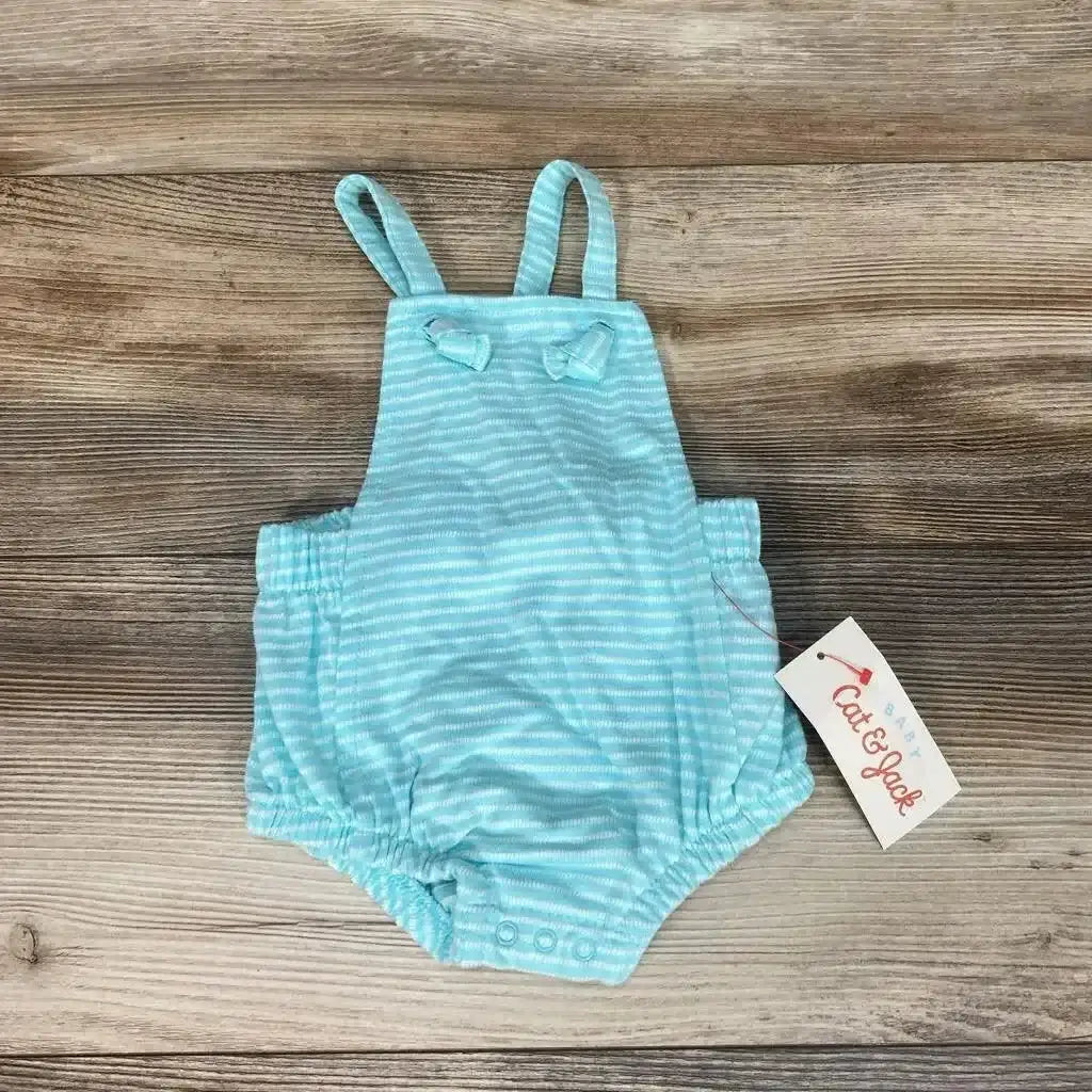 Flat lay of Cat & Jack striped infant romper, 0-3M, with straps, bows, elastic leg cuffs and snap crotch on wood background