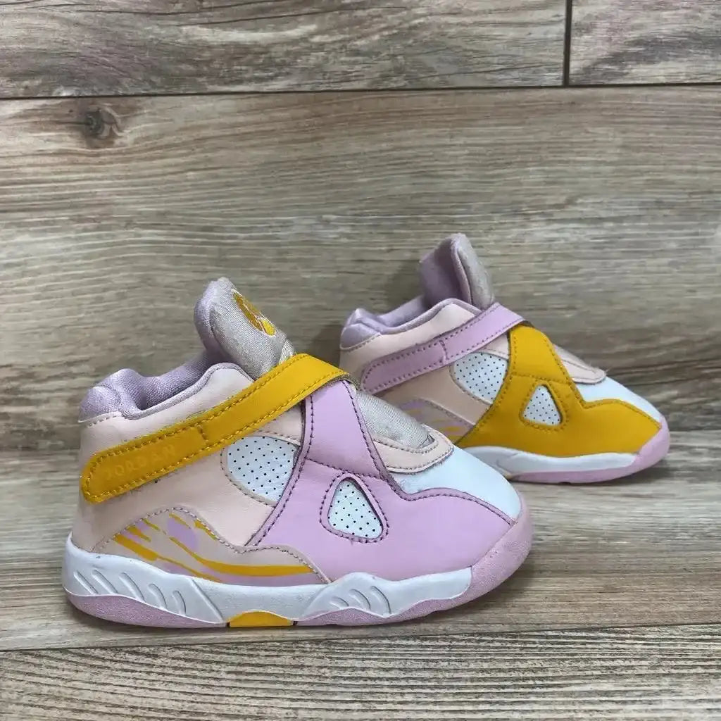 Side view of Air Jordan 8 Retro GS Arctic Punch showcasing pink and white upper with yellow accents and strap on wood plank floor