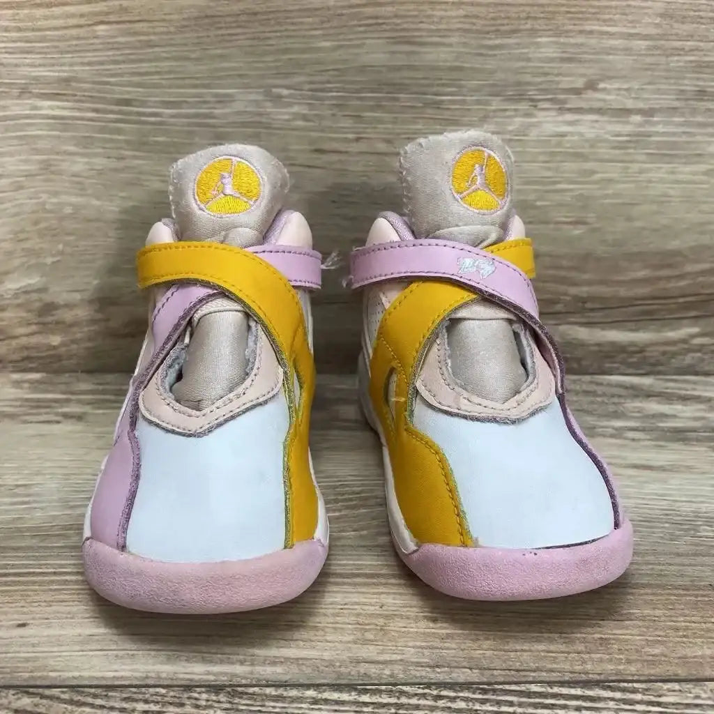 Front view of Air Jordan 8 Retro GS Arctic Punch sneakers showcasing pink yellow and white panels with Jumpman logo on wood plank floor