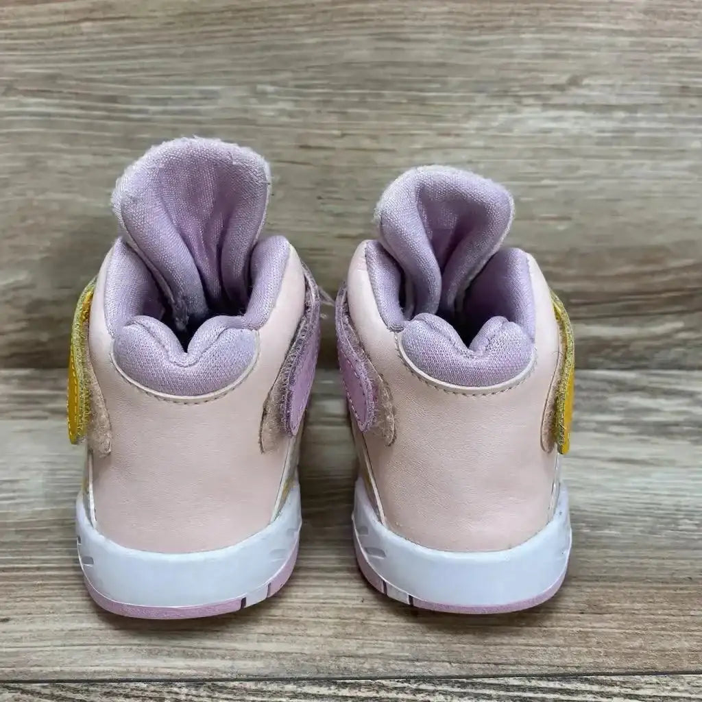 Back view of Air Jordan 8 Retro GS Arctic Punch showcasing pink leather heels with lilac collar and yellow accents on wood plank floor