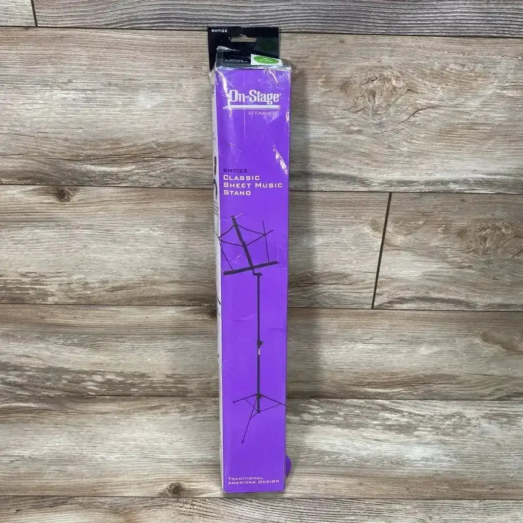 Top view of On-Stage Stands classic sheet music stand in sealed purple retail box on wood plank floor