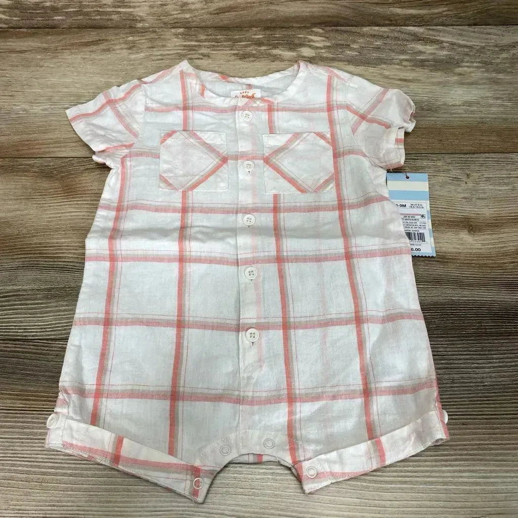 Top-down view of white romper with coral plaid showing front button placket, two chest patch pockets, short sleeves, and snap crotch closures on a wood background
