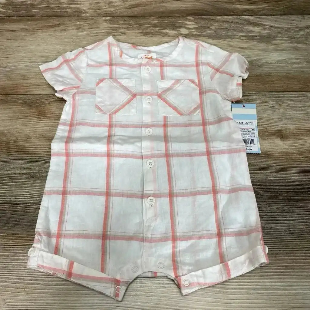 Top-down view of white romper with coral plaid showing front button placket, two chest patch pockets, short sleeves, and snap crotch closures on a wood background