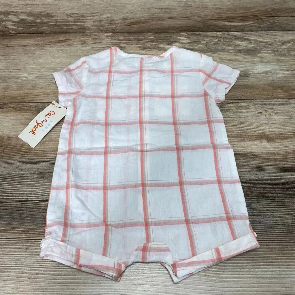 Flat-lay white baby shortie romper with coral-pink plaid, short sleeves and rolled hems, Cat & Jack tag on wood surface