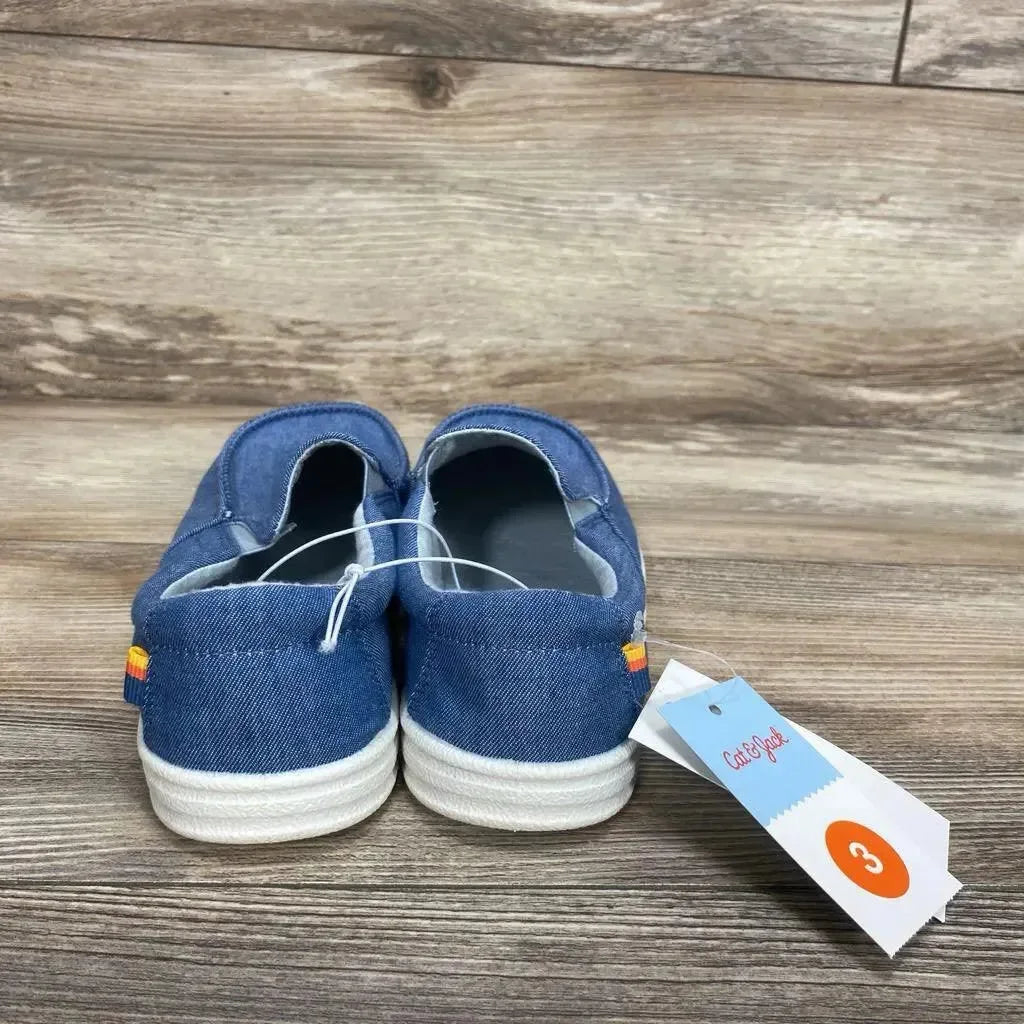 Rear view of blue Cat & Jack slip-on sneakers size 3Y showing denim canvas, white soles, heel rainbow tab on wood background
