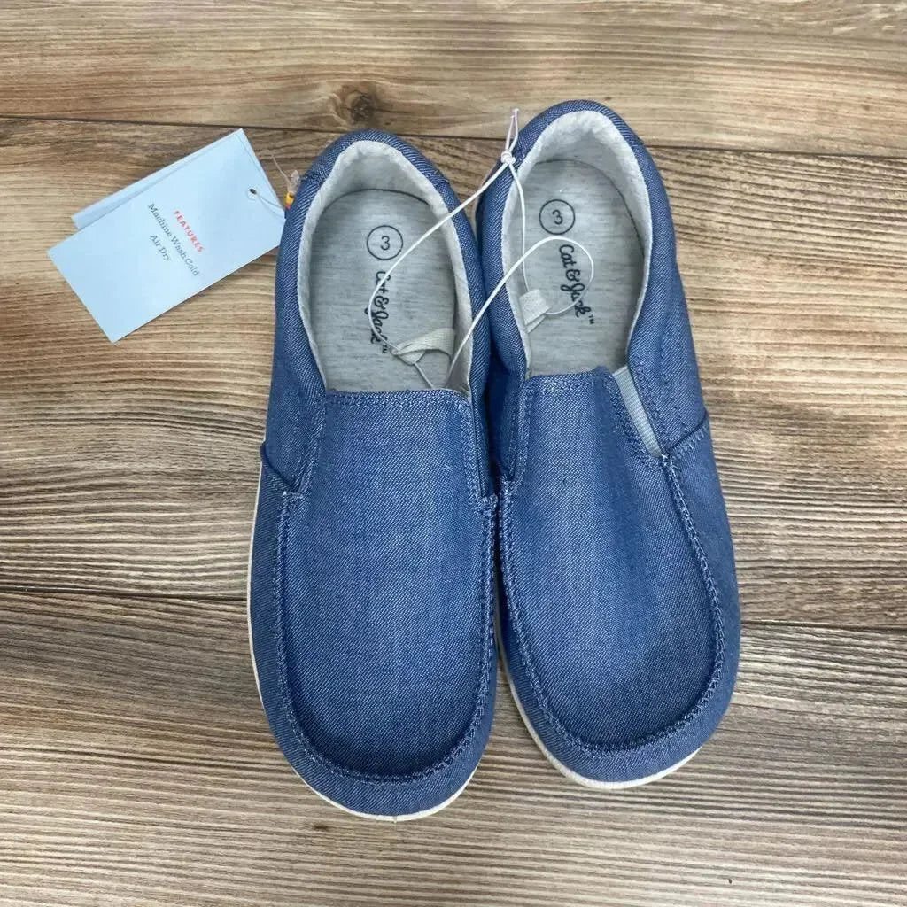 Overhead view of Cat & Jack Bergen blue slip-on toddler sneakers with elastic sides and white rubber soles on wood background
