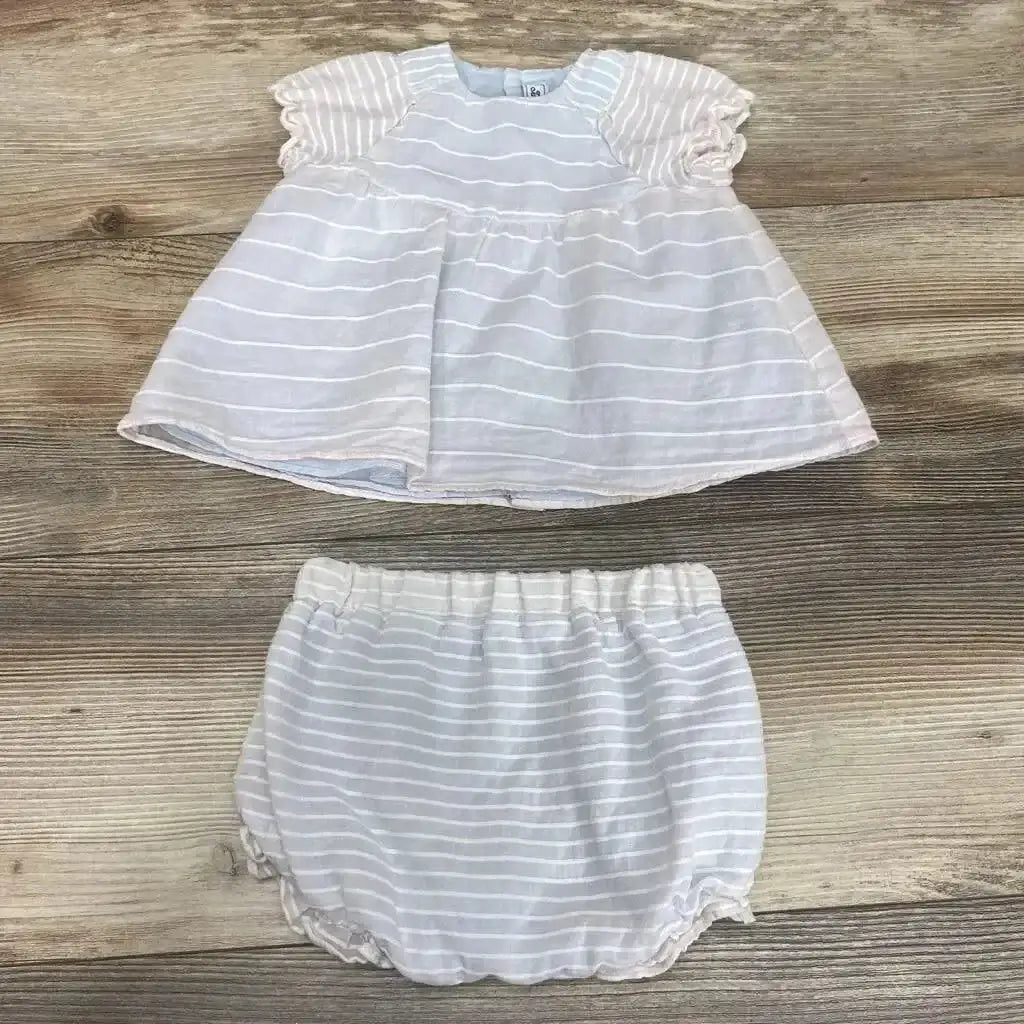Flat lay of Tartine et Chocolat piping dress set showcasing pastel pink and blue striped dress with matching bloomers on wood plank floor