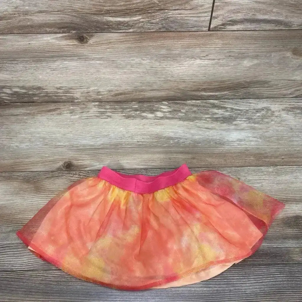 Flat lay of toddler pink-orange Paw Patrol tutu skirt showing elastic hot-pink waistband and layered tulle on wood floor