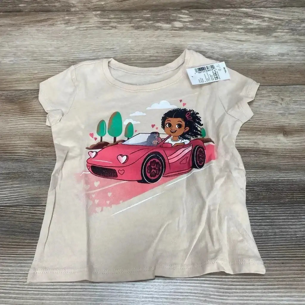 Flat-lay of beige Children's Place toddler graphic tee size 18-24 months showing girl driving pink car graphic on gray wood floor