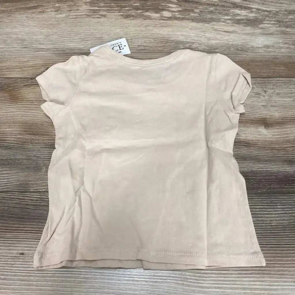 Back view flat lay of beige Children’s Place toddler short-sleeve shirt showing crew neck and visible size tag on wood floor
