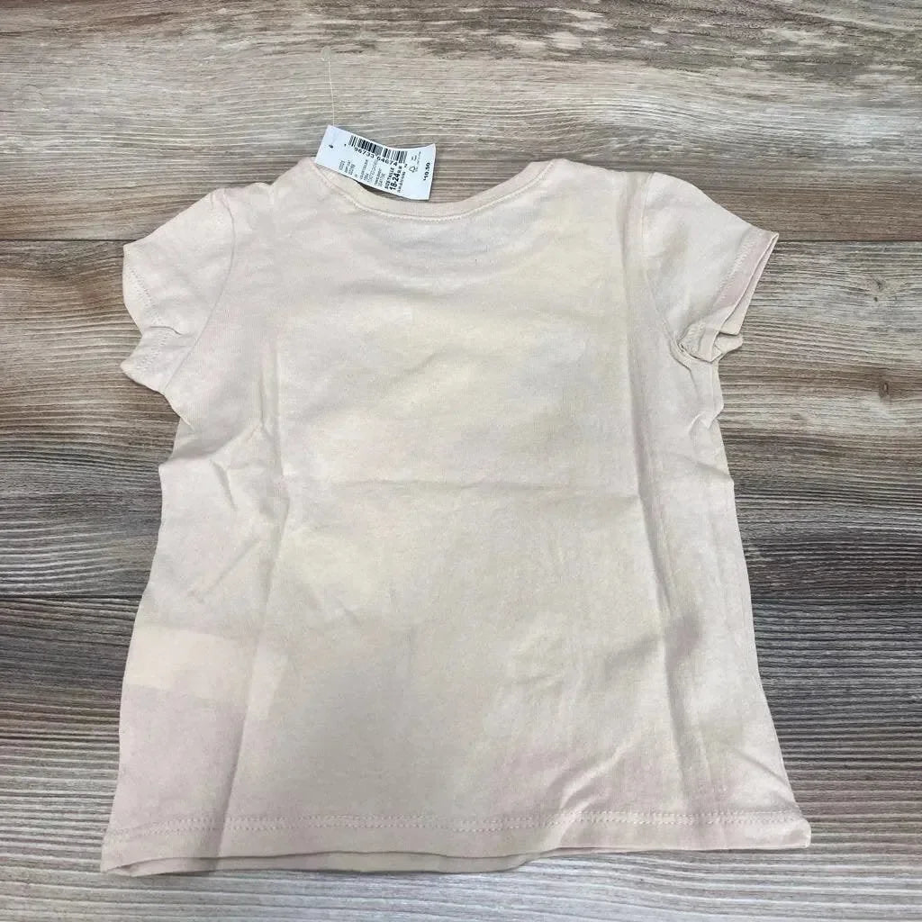 Back view of beige toddler short-sleeve t-shirt showing plain back and collar tag, laid flat on wood background