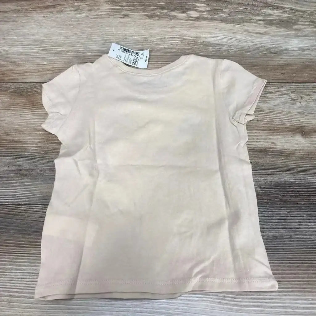 Back view of beige toddler short-sleeve t-shirt showing plain back and collar tag, laid flat on wood background