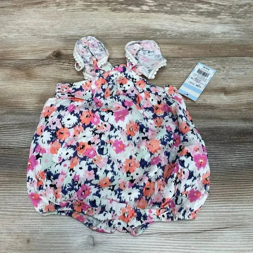 Top-down view of Cat & Jack pink floral flutter-sleeve baby romper (0-3M) showing ruffled shoulder straps and snap crotch on wood background