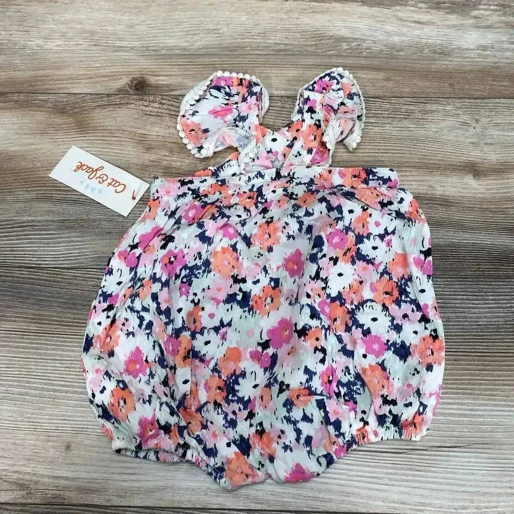 Flat lay of NWT Cat and Jack flutter sleeve romper in navy white pink and orange floral print with smocked bodice and hangtag on wood plank floor