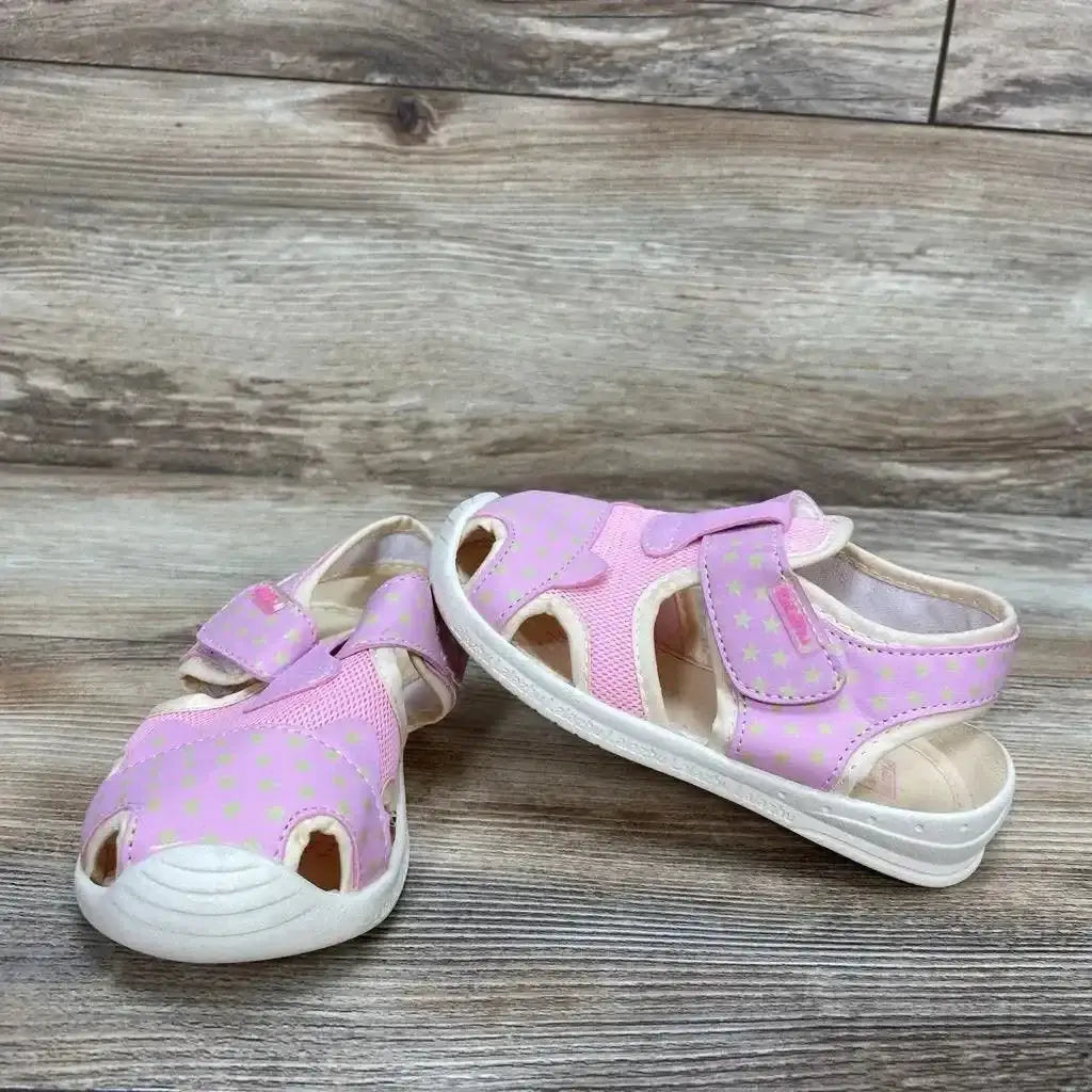 Three-quarter view of pink toddler sandals with closed-toe, star-print microfiber upper and Velcro strap on wood background