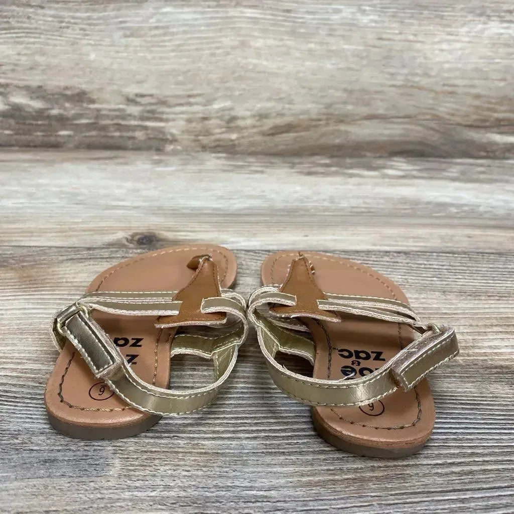 Top-front view of Zoe & Zac toddler gold sandals showcasing metallic straps and Velcro ankle closures on weathered wood background