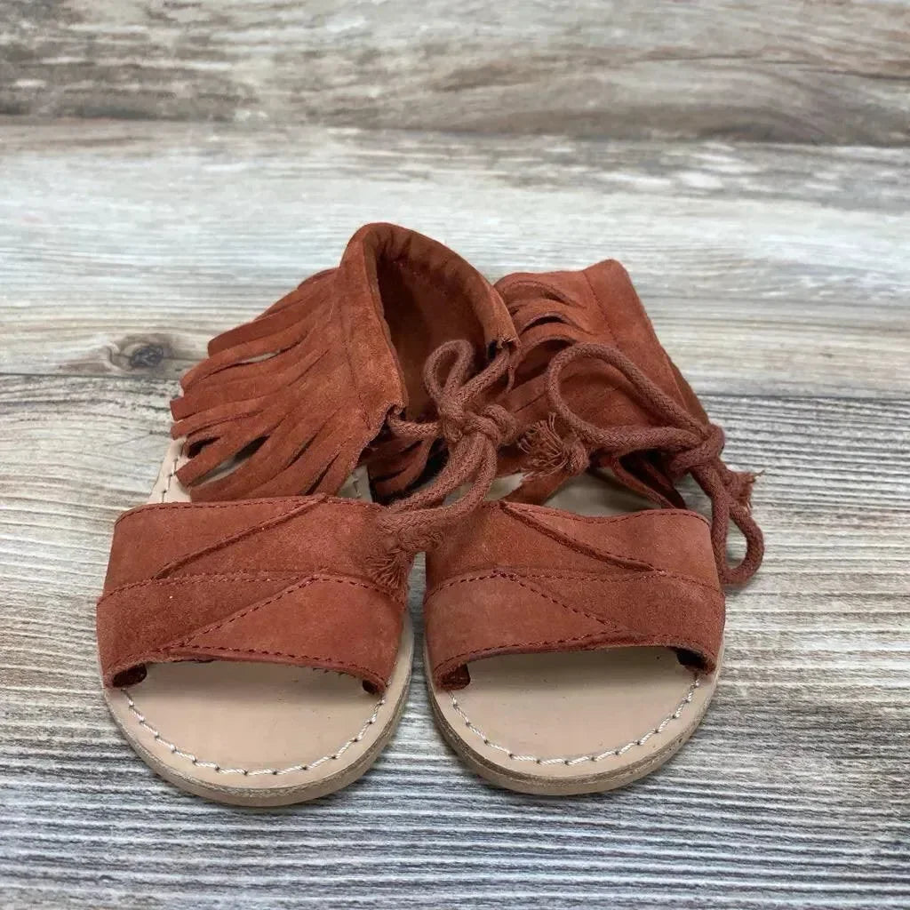 Front view of Zara baby fringe sandals size 4C showing red suede toe strap, ankle fringe and wrap ties on wood background