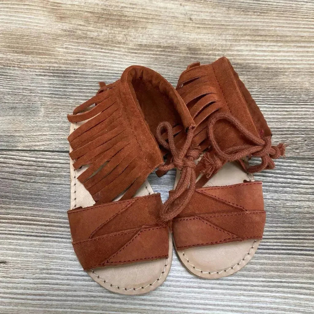 Top view of Zara baby fringe sandals size 4C showcasing rust suede fringe ankle ties and stitched tan insoles on wood background