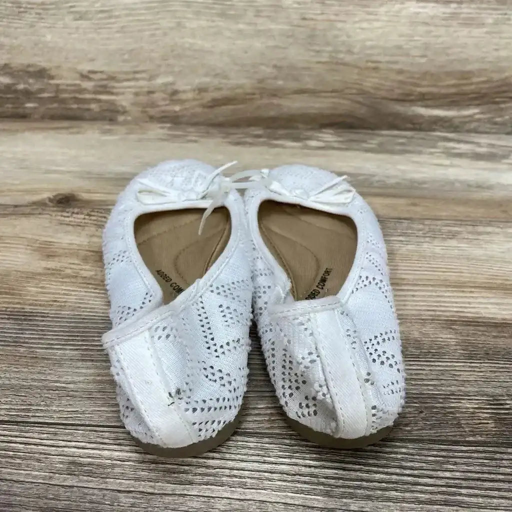 Top view of white toddler bow ballet flats showcasing lace eyelet pattern and small front bows on wood floor
