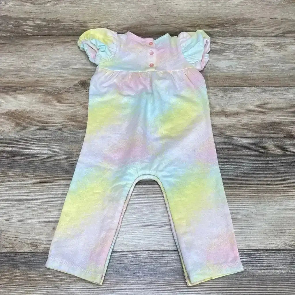 Flat lay of First Impressions baby romper in pastel tie-dye with puff sleeves and three-button front, on wood background