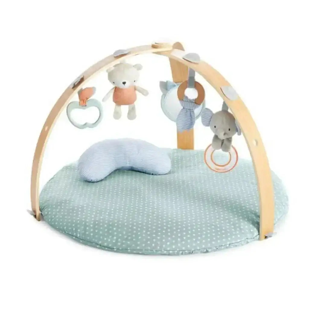 Front view of Ingenuity Cozy Spot activity gym with green polka-dot mat, wooden arches and hanging plush toys on white