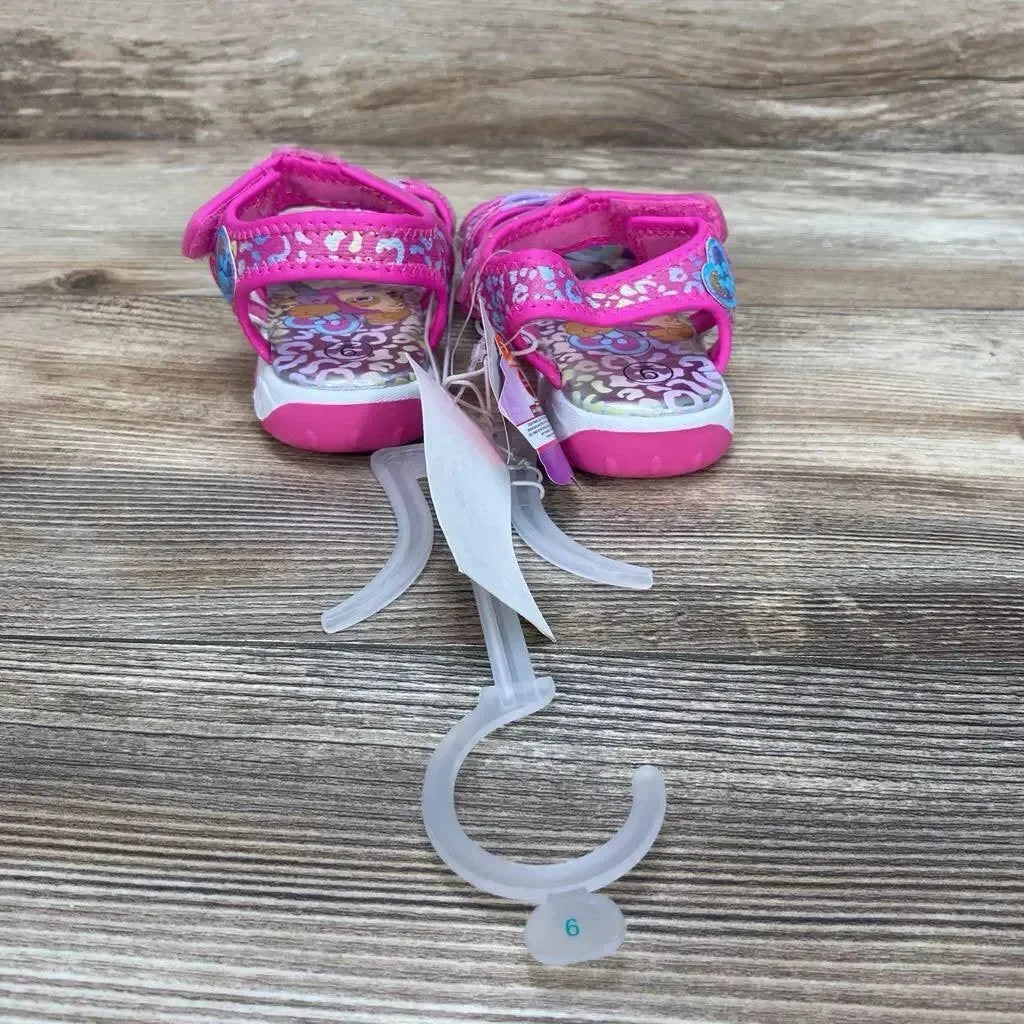 Front view of pink Paw Patrol ankle-strap sandals showing patterned insole and Velcro ankle straps on wood surface