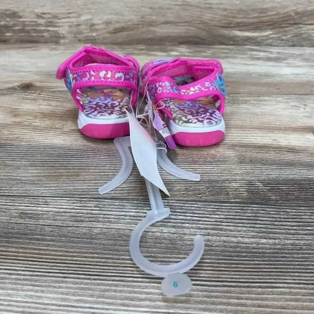 Back view of NWT Paw Patrol Adventure ankle strap sandals sz 9c showcasing pink straps with character print and hangtag on wood plank floor