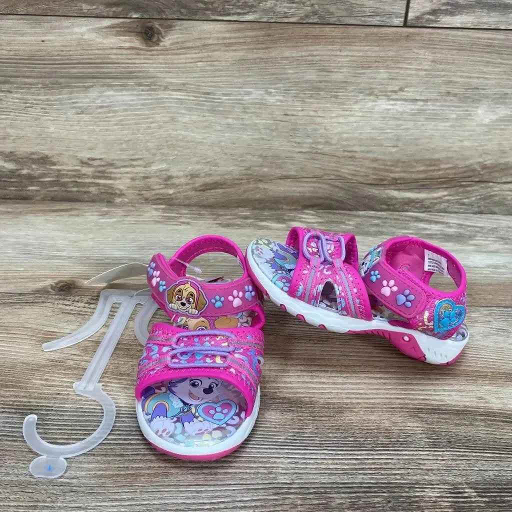 Front view of NEW Paw Patrol Adventure ankle strap sandals in pink with Skye graphic on wood plank floor