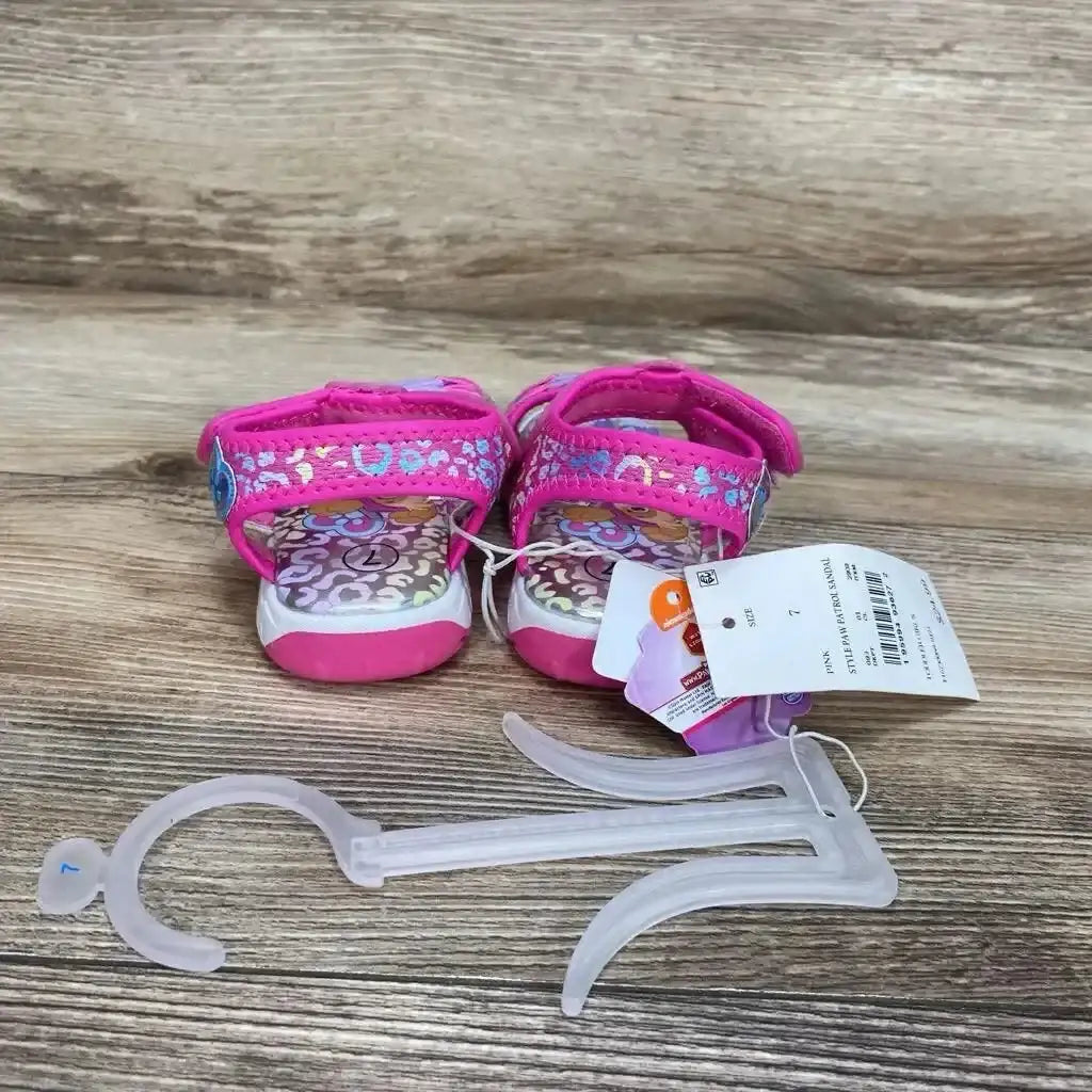 Back view of pink Paw Patrol ankle-strap sandals size 7C with patterned insoles, Velcro straps, tags, and plastic hanger
