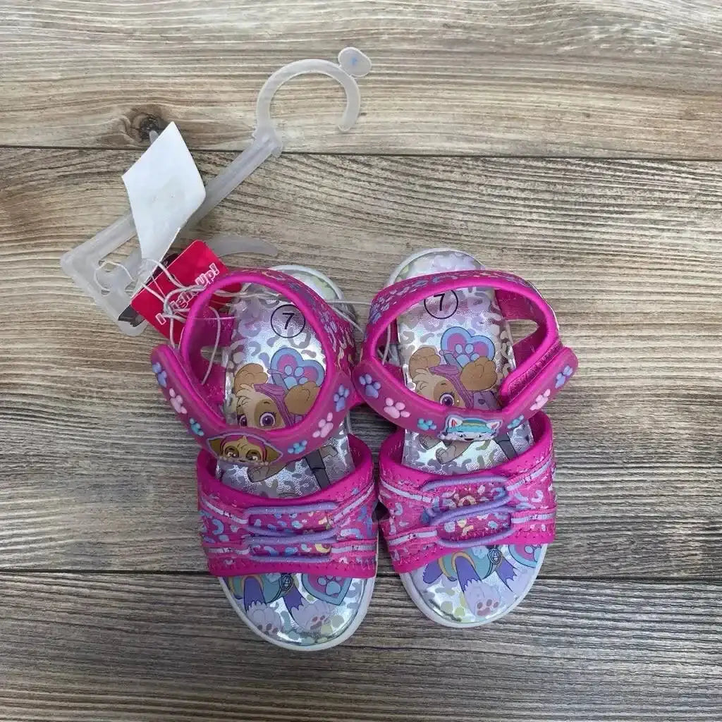 Top view of pink Paw Patrol ankle-strap sandals size 7C with two front straps and Velcro ankle strap on wood floor