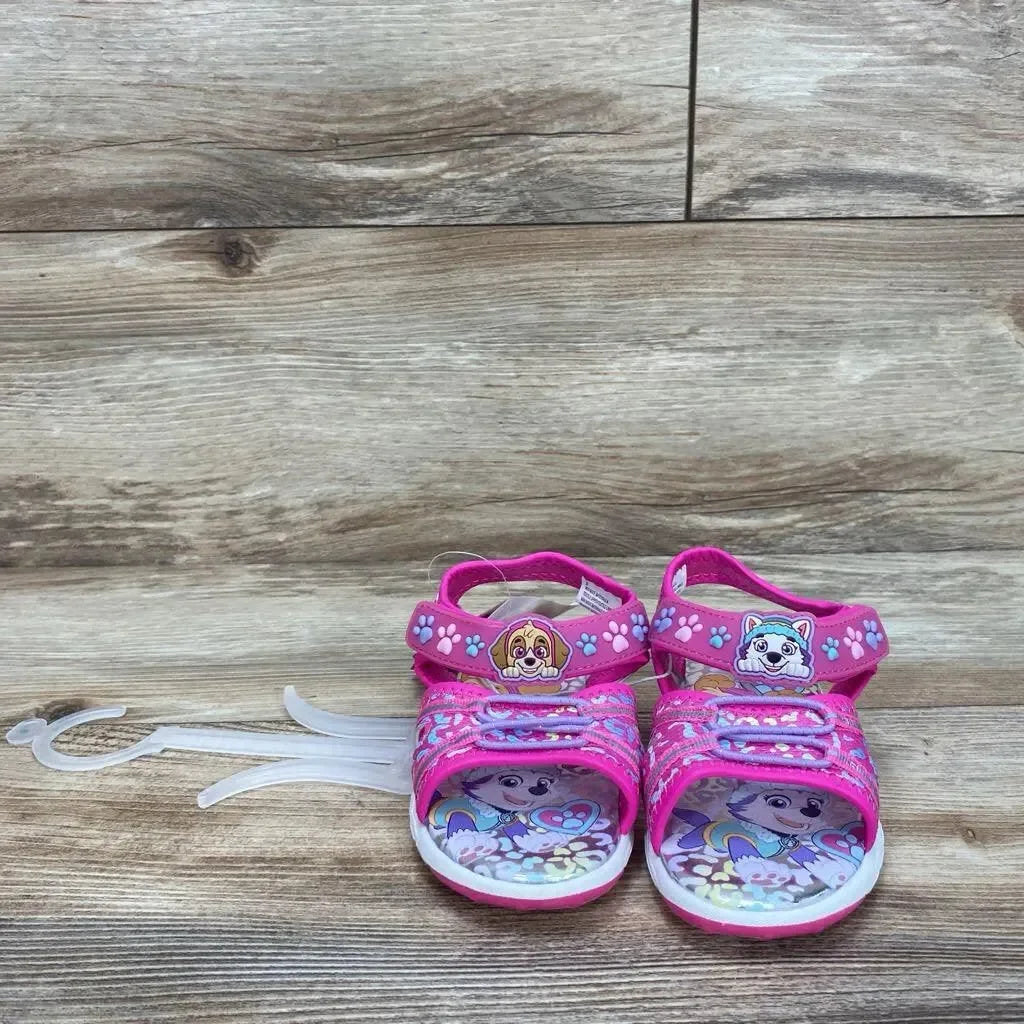 Front view of pink Paw Patrol Adventure ankle-strap toddler sandals, adjustable Velcro straps and character-printed insoles on wood background