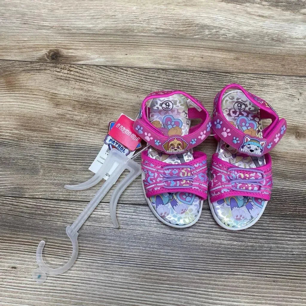 Top view of pink Paw Patrol toddler ankle-strap sandals size 9C showing double Velcro straps and character accents on wood