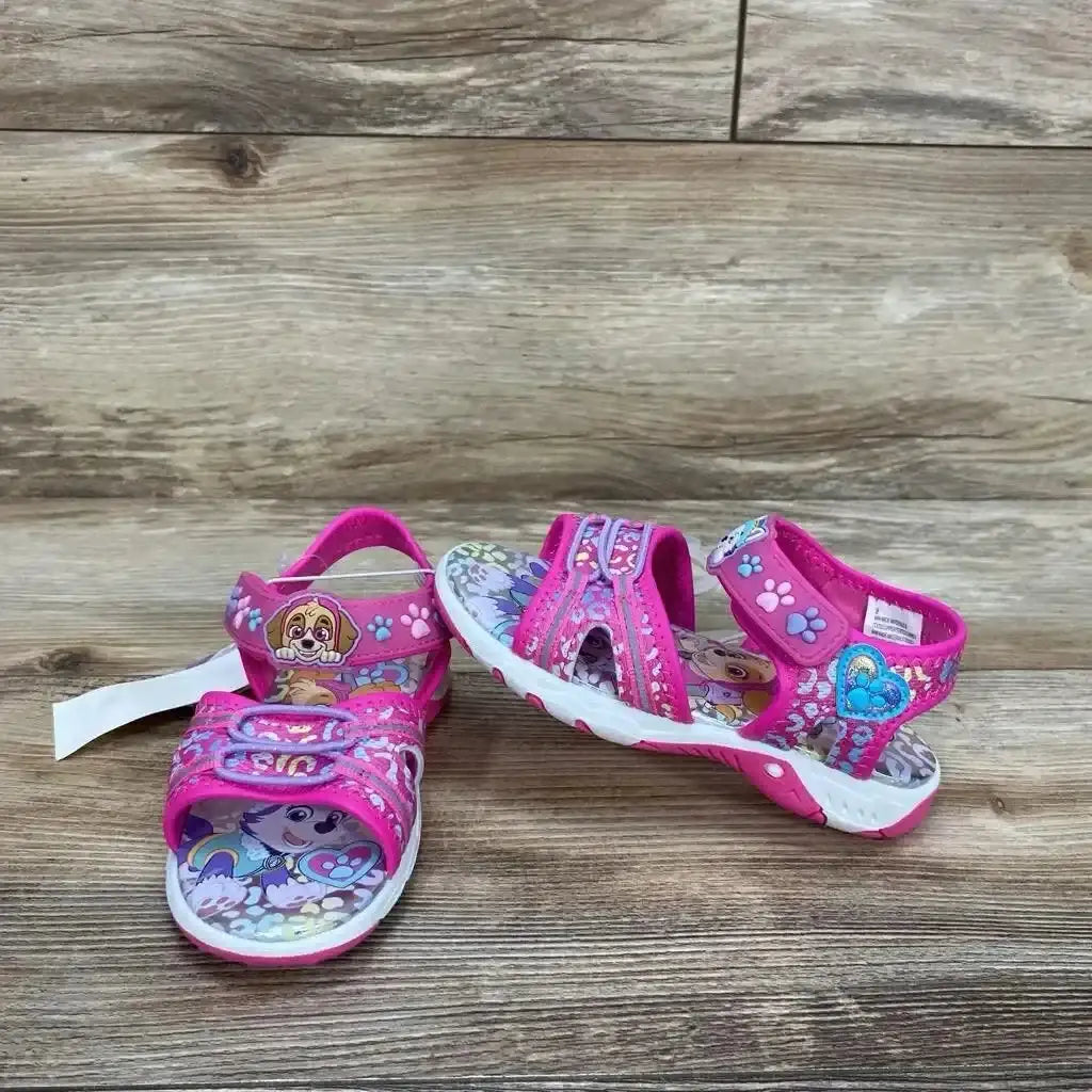 Three-quarter view of pink Paw Patrol toddler sandals with Velcro straps, character footbed print, and white soles