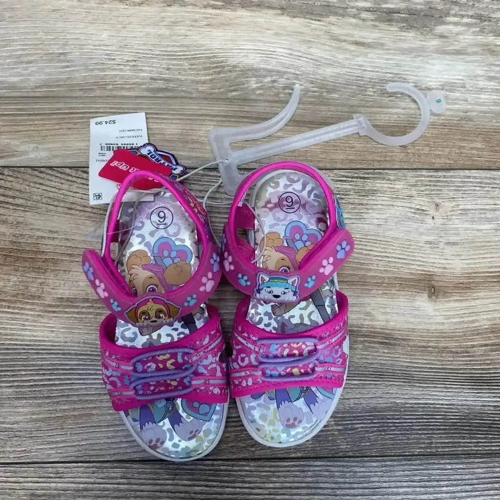 Overhead view of pink Paw Patrol ankle-strap sandals size 9C showing Velcro straps and character insoles on wood floor