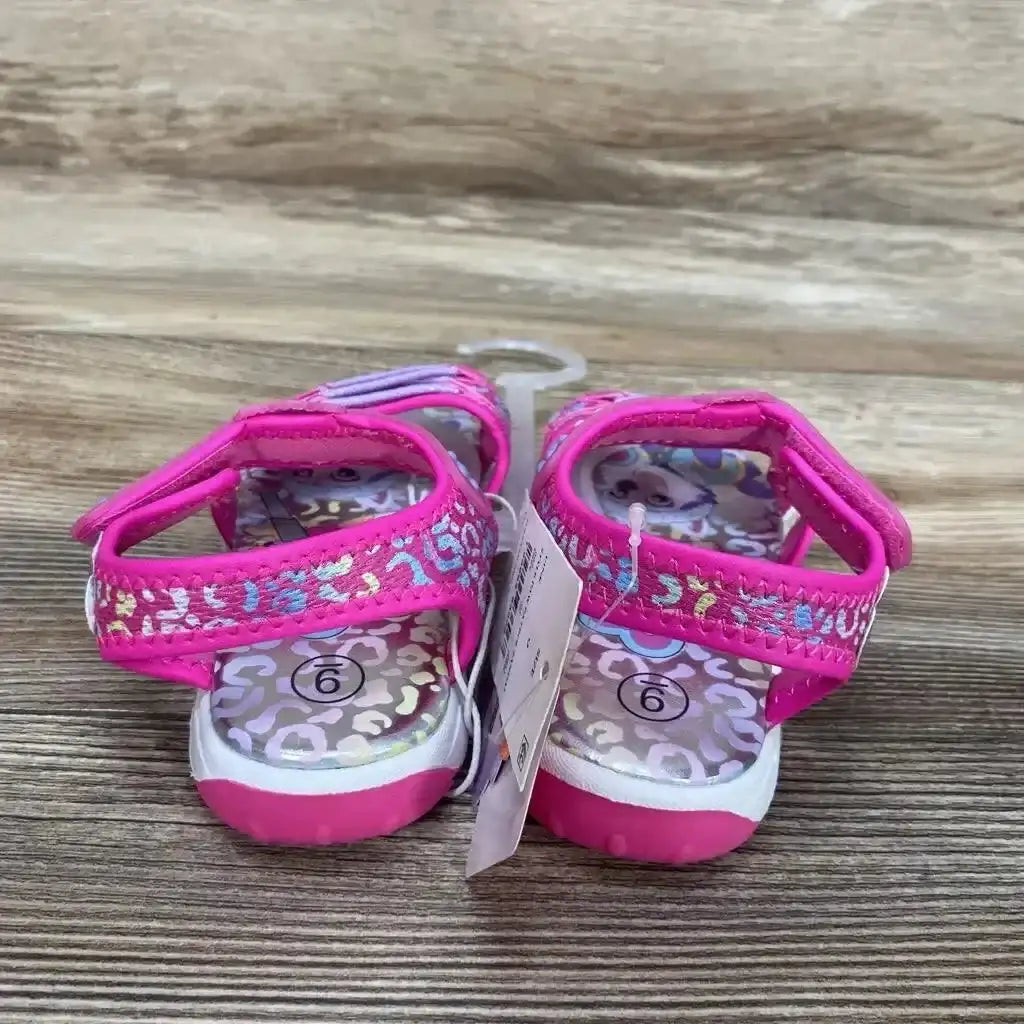 Rear view of pink Paw Patrol toddler ankle-strap sandals with Velcro, iridescent leopard footbeds and size 6 stickers on wood