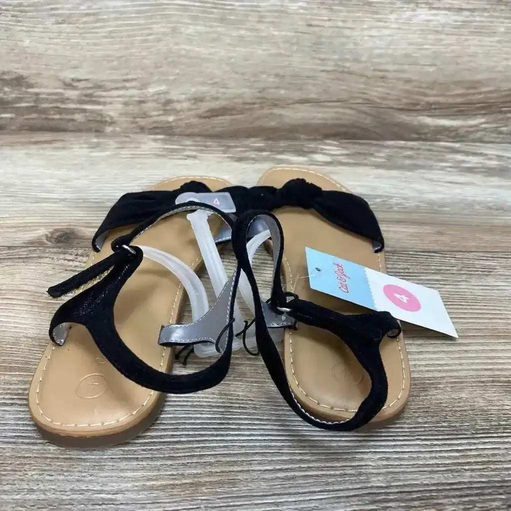 Three-quarter view of new Cat and Jack Lydia sandals size 4Y in black with bow detail and tan footbed with hangtag on wood plank floor