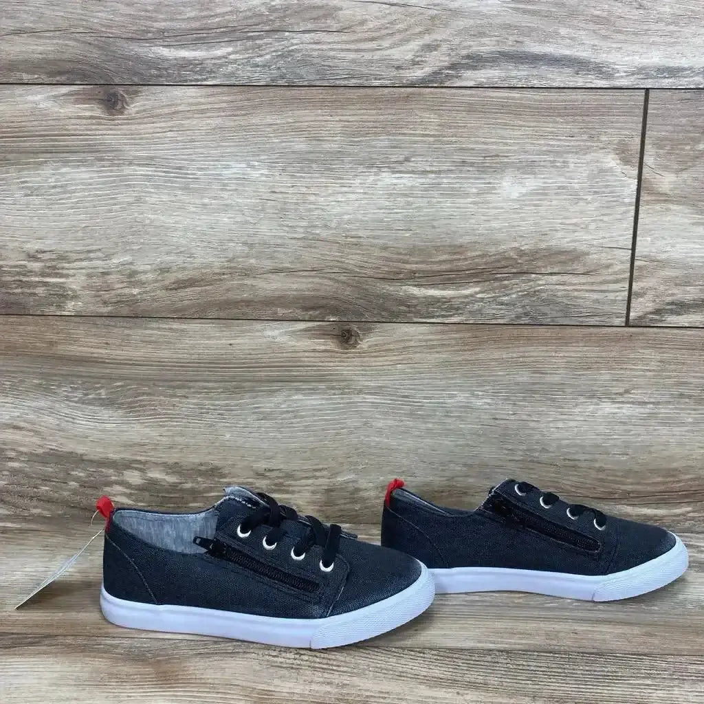 Three quarter view of NWT Cat and Jack Lucian double zipper sneakers in black canvas with white sole and red heel tab on wood plank floor