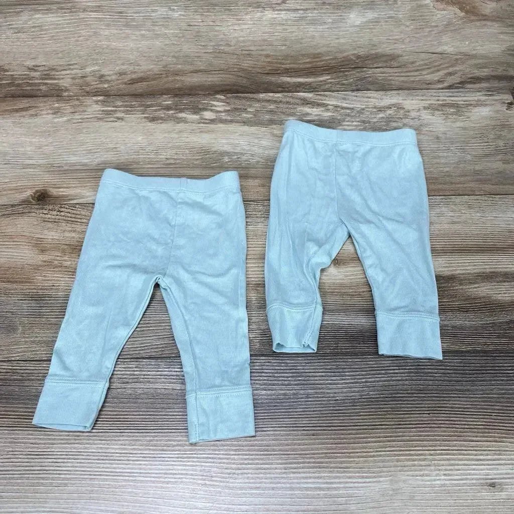 Flat lay of two light green Cloud Island modal newborn pants showing fold-over cuffs and elastic waist on wood background