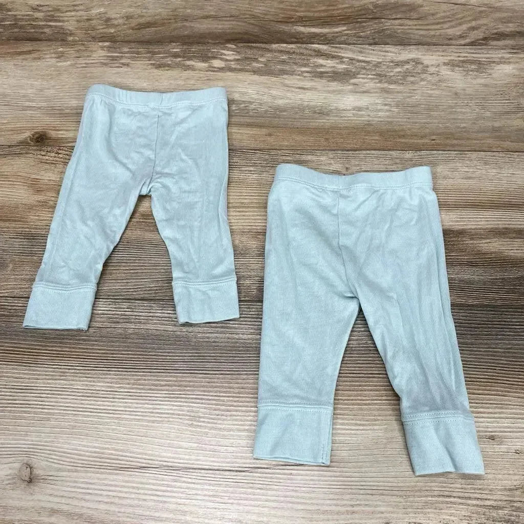 Flat-lay of two Cloud Island newborn modal pants in light sage green showing ribbed fabric and fold-over cuffs on a wood surface