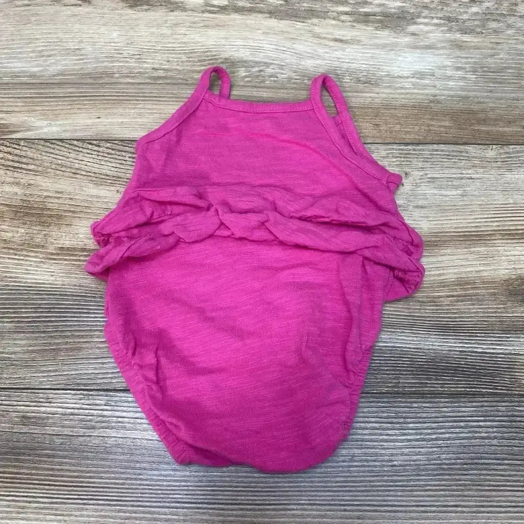 Flat lay of Carters floral romper in heathered pink with spaghetti straps and ruffle bodice on wood plank background