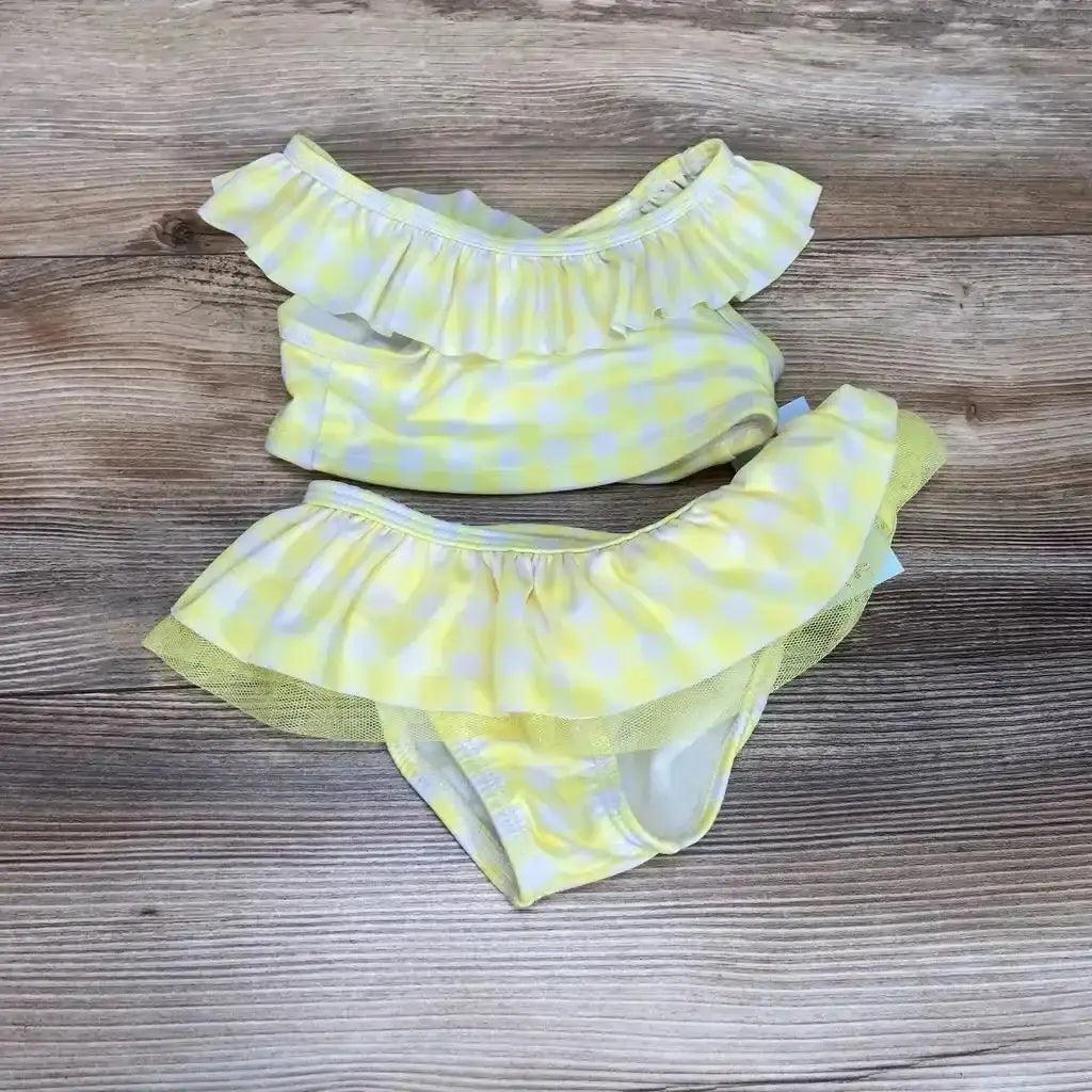 Top-down of yellow gingham 2-piece baby bikini (18m) with ruffled off-shoulder top and tulle-trim bottoms on wood background